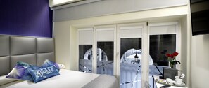A modern hotel room with a bed, a desk with a computer, and a view of the outside. - Pensión Plaza Nueva (Bilbao)