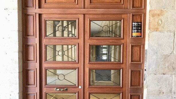 A wooden double door with glass panels and a number '1' above it. - Pensión Plaza Nueva (Bilbao)