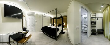 Camera d'albergo moderna con letto a baldacchino, una scrivania con sedia, TV a parete e bagno con doccia e WC.