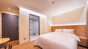 Una habitación de hotel con cama, escritorio y zona de ducha.
