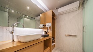 Un baño moderno con un lavabo grande de color blanco, cabina de ducha de vidrio y tocador de madera.
