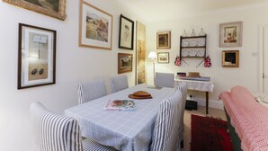 Un coin repas avec une table dressée pour quatre personnes, des chaises à rayures et un tapis aux motifs rouges et blancs.