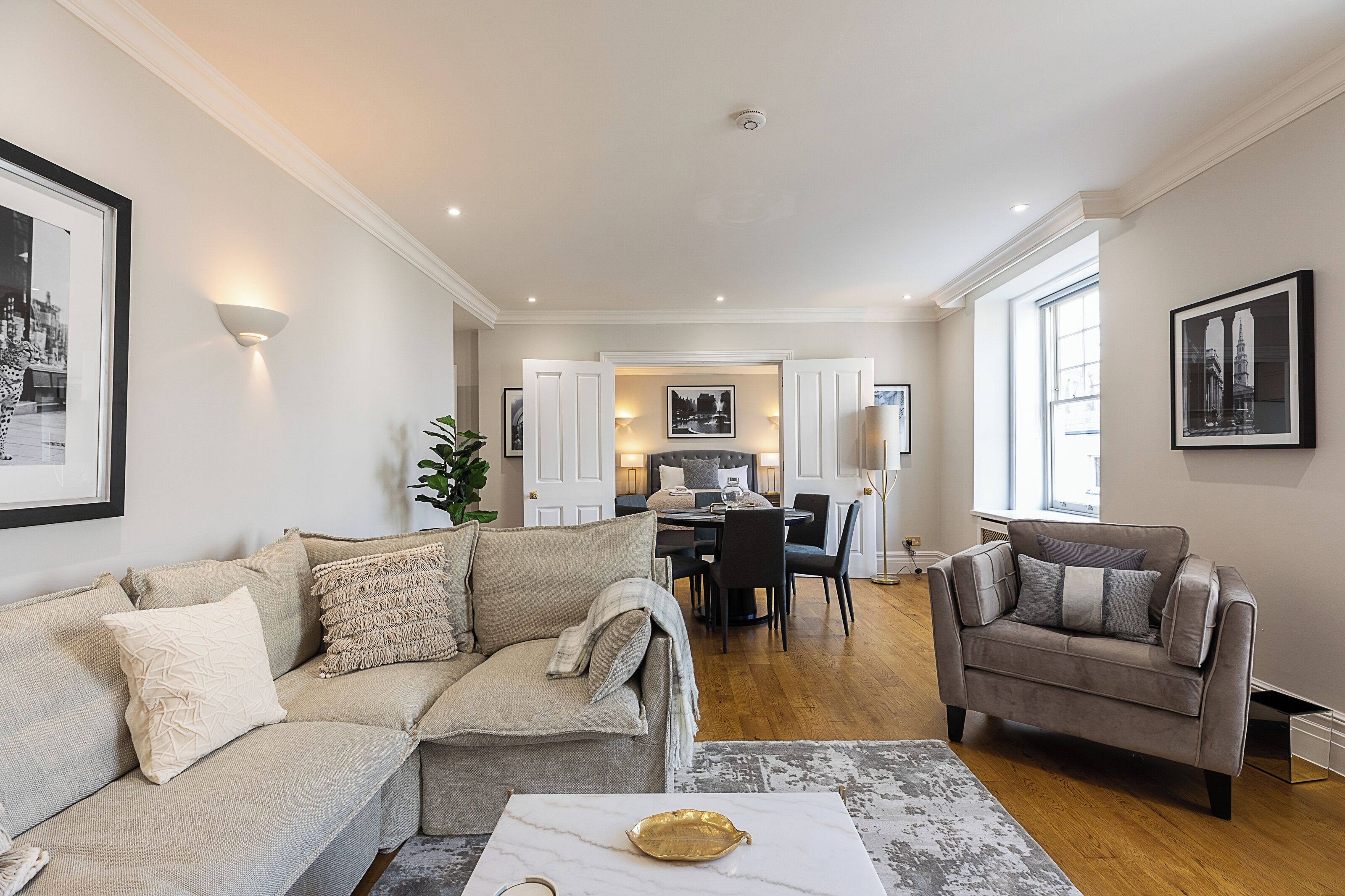A spacious living area with a sofa, armchair, and a dining table.