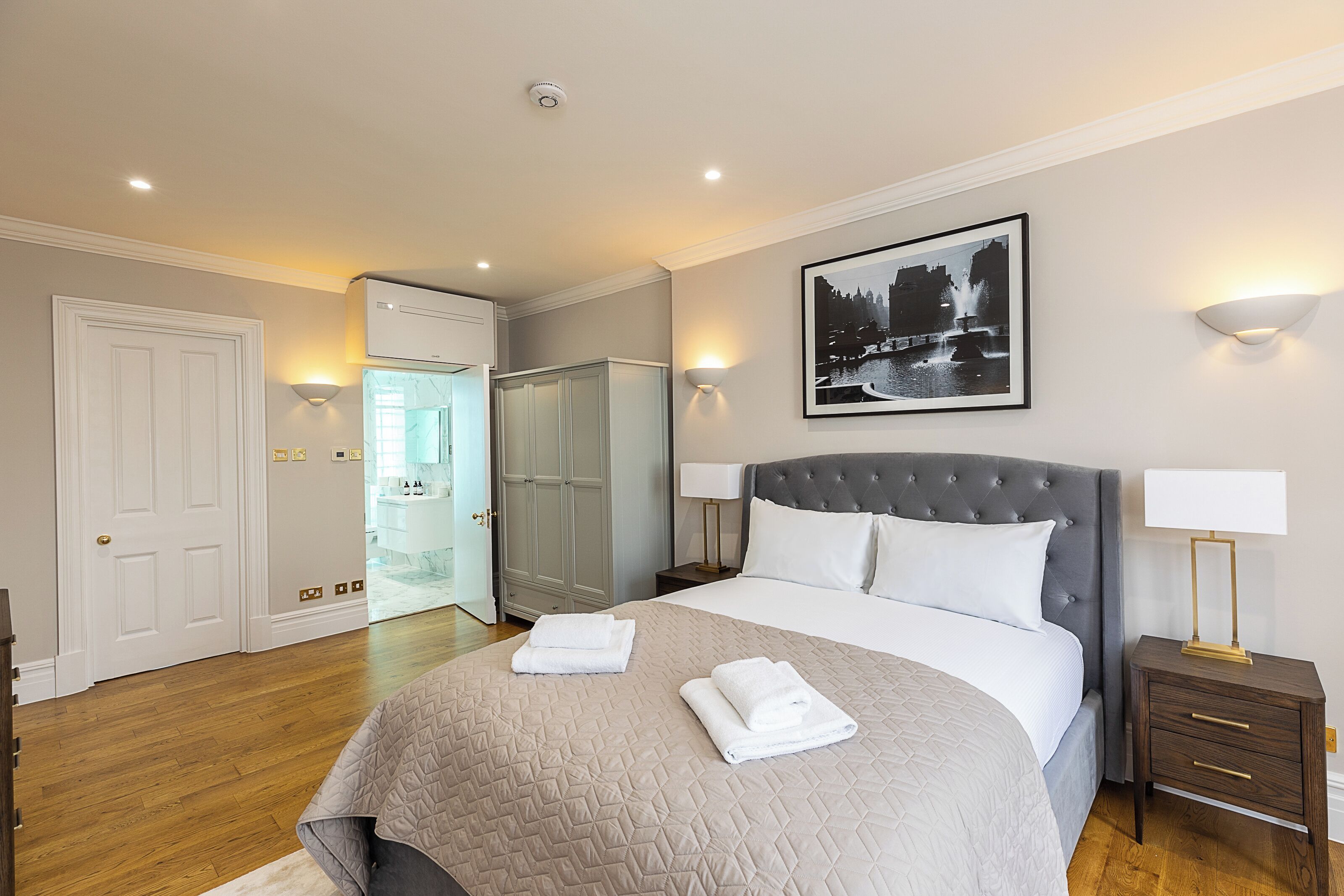 Una camera d'albergo con un letto grande, un armadio, un bagno e un quadro appeso al muro.