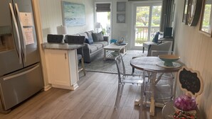 Une cuisine moderne dotée d’un réfrigérateur encastré, un coin repas avec une table ronde et un salon avec un canapé et une table basse.