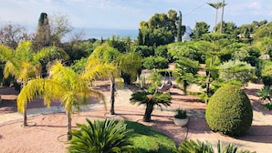 A garden with various plants and trees, a swing, and a view of the sea. - B&B Casa Pedramala (Benissa)