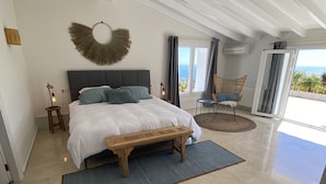A bedroom with a large bed, a bench, a wall-mounted light fixture, and a view of the outdoors. - B&B Casa Pedramala (Benissa)