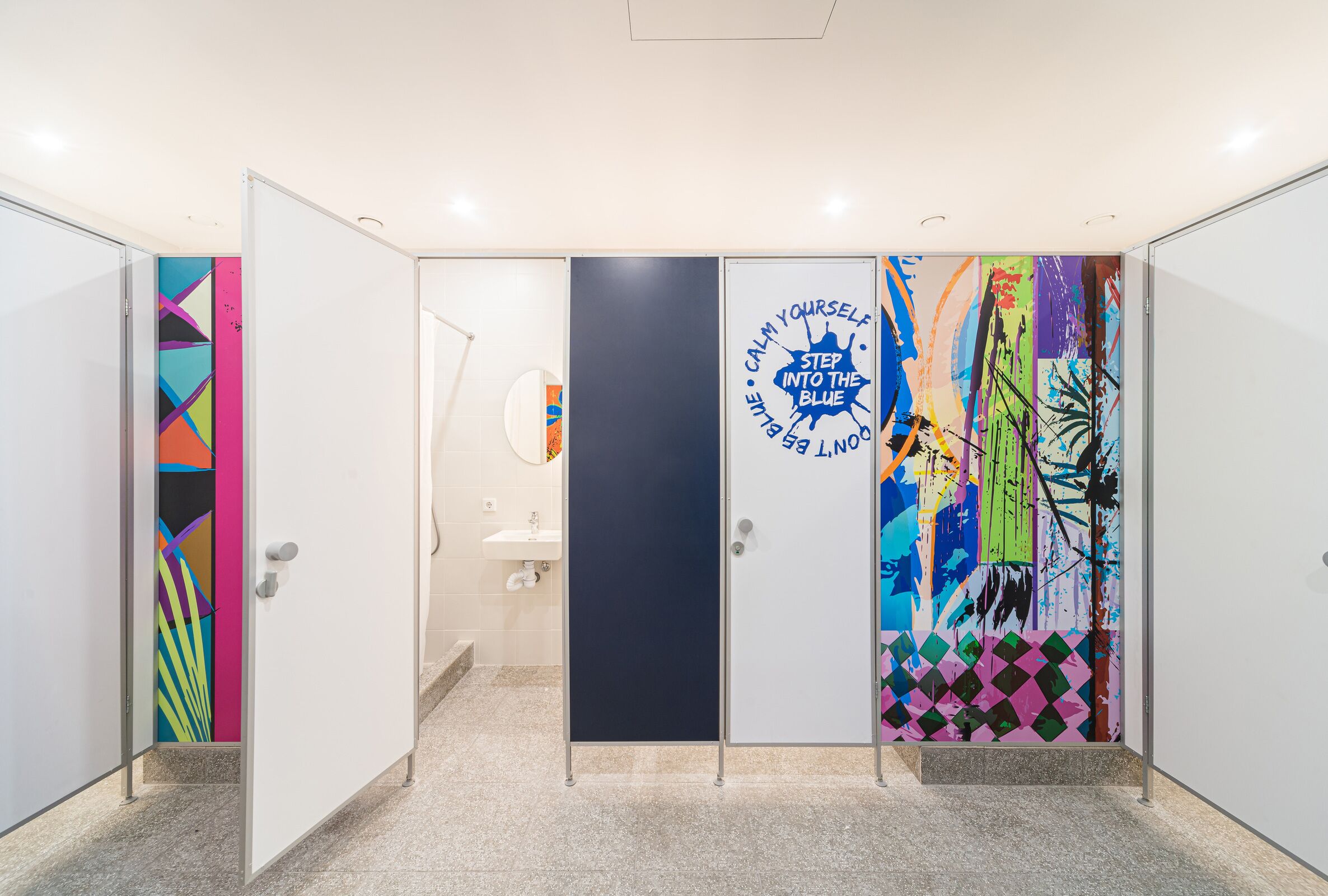 A hallway with lockers, a sink, and a door with a motivational poster.