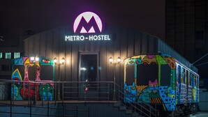 A metro hostel with a distinctive neon sign, colorful graffiti, and a staircase leading to the entrance. - Metro Hostel (Kyiv)