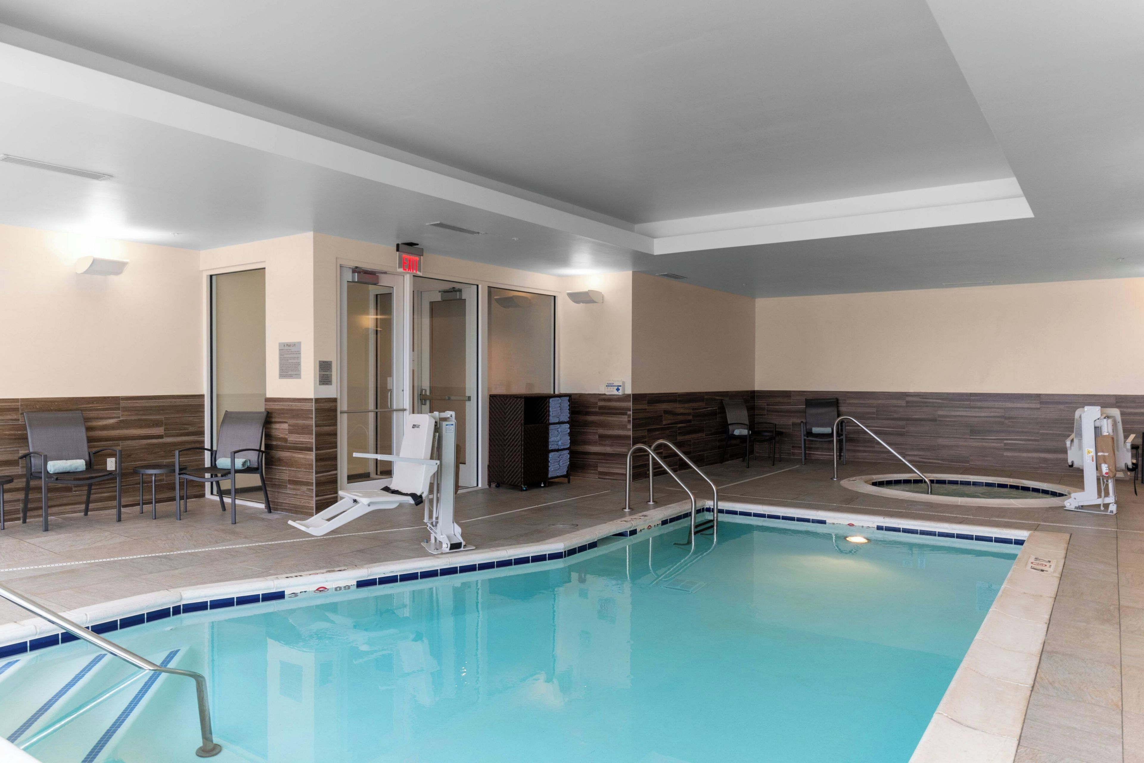 Zona de piscina con silla de socorrista, escalera de piscina y banco.