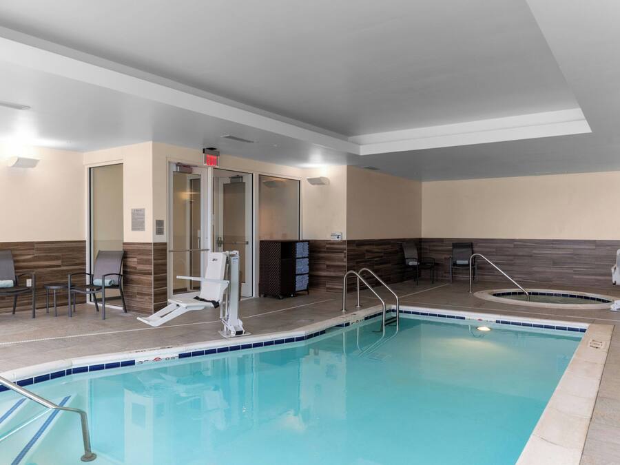Zona de piscina con silla de socorrista, escalera de piscina y banco.