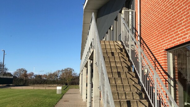 A staircase leading to a building with a brick facade and a clear blue sky in the background. - NIKC Sleepover (Nibe)