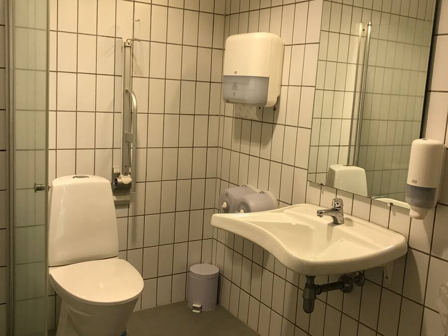 A small, tiled bathroom with a toilet, sink, and hand dryer.