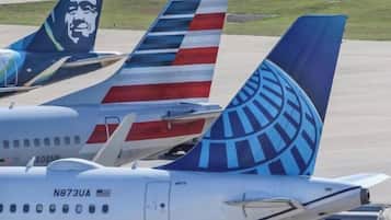 Tres aviones estacionados en un aeropuerto, con diseños visibles en sus colas y números de registro.