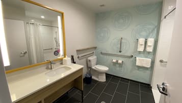 A modern bathroom with a large mirror, a sink, a toilet, and a shower area.