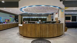 Un mostrador de recepción de hotel con detalles de madera, una pantalla digital y un cartel de Hilton.