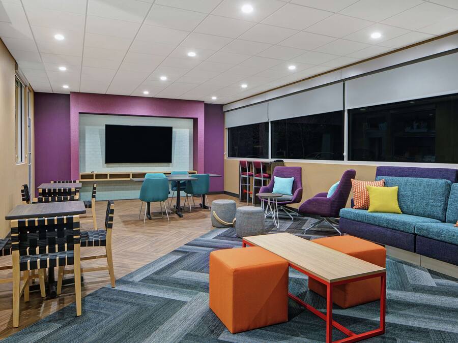 A modern lounge area with a large screen, comfortable seating, and a carpeted floor.