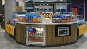 Una estación de bebidas de autoservicio con una sección refrigerada y un microondas.