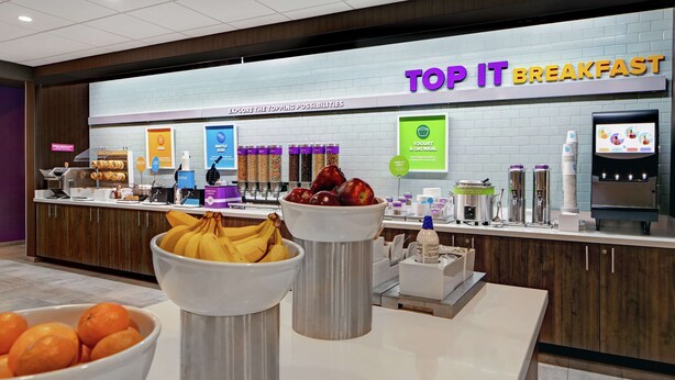 Zona de desayuno tipo buffet con diversas opciones de comida y una presentación de yogur y cereales.