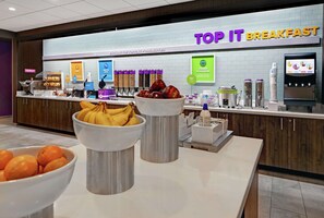 Zona de desayuno tipo buffet con diversas opciones de comida y una presentación de yogur y cereales.