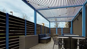 Un patio exterior con zona de estar techada, una mesa y sillas.
