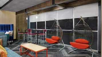 Un espacio de oficina moderno con sofá, sillón colgante, una mesa y una mesa de reuniones con sillas.