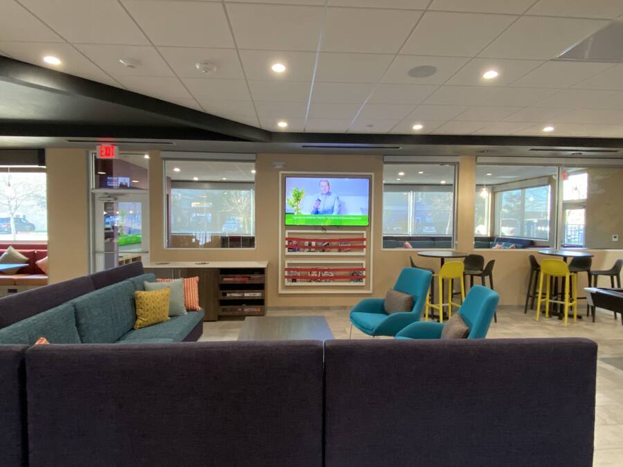 A modern lounge area with a sofa, chairs, a TV screen, and a bookshelf.