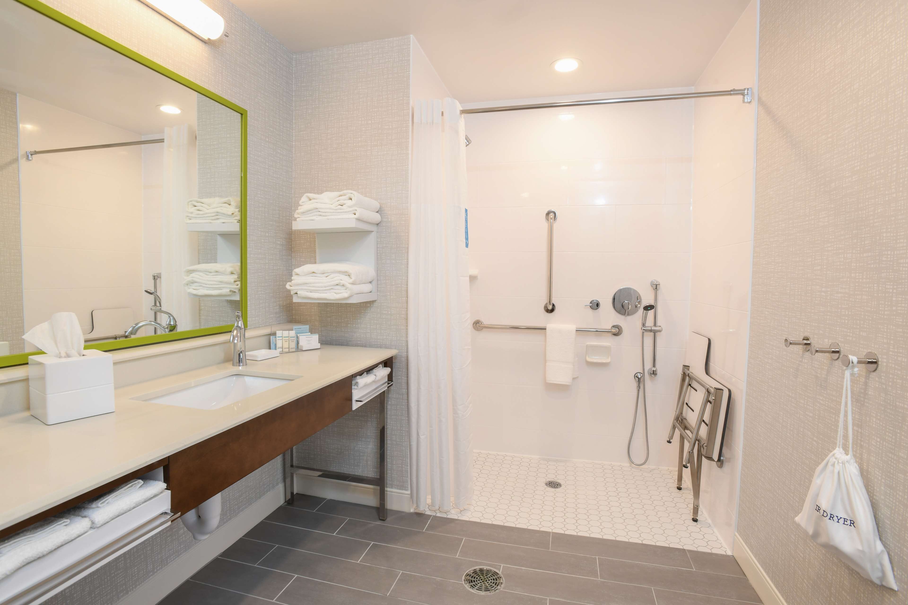 Een moderne badkamer met dubbele wastafels, een douche met glazen deur en een handdoekrek.