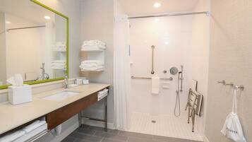 Un baño moderno con lavamanos dobles, ducha con puerta de vidrio y perchero para toallas.