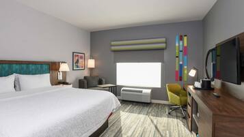 Habitación de hotel con una cama grande, un escritorio, una silla, un televisor y una ventana con persianas.