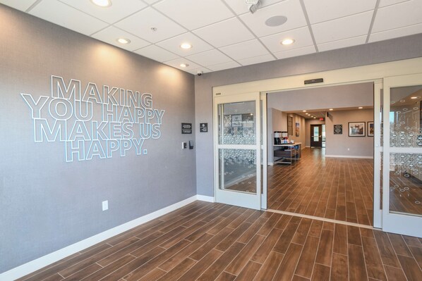 A modern interior with a motivational wall message, a wooden floor, and a glass door leading to another room. - Hampton Inn & Suites Cincinnati Liberty Township (West Chester)