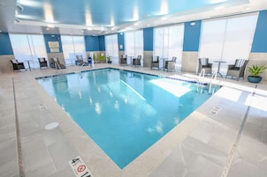 Una piscina interior con agua cristalina, rodeada de sillas y mesas de descanso.