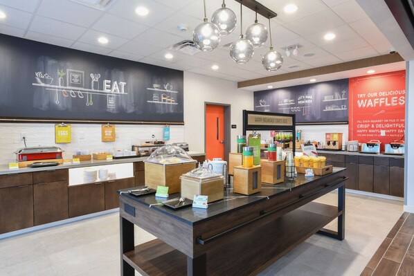 A breakfast buffet area with various food stations, including a waffle station, and a chalkboard menu. - Hampton Inn & Suites Cincinnati Liberty Township (West Chester)