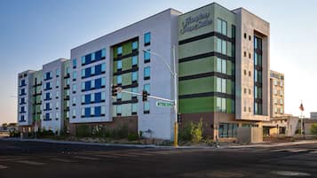 Un hotel moderno con varios pisos y una señalización destacada para Hampton Inn & Suites.