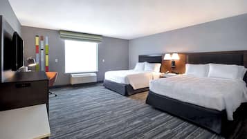Quarto de hotel com duas camas, uma escrivaninha, uma televisão e uma janela com persianas.