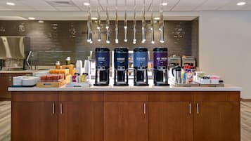 A modern kitchen area with a coffee station featuring four coffee makers labeled Decaf, Robust, Regular, and Hot Water.