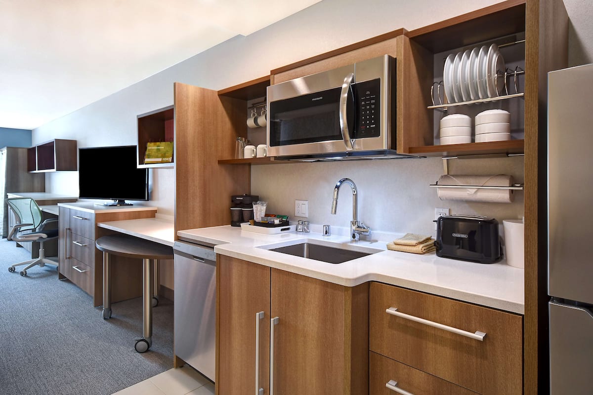Een moderne keuken met roestvrijstalen apparatuur, houten keukenkastjes en een inbouw vaatwasser.
