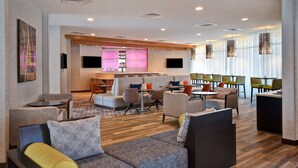 Eine moderne Hotelhalle mit Sitzbereichen, einer Bar und einem Fernsehbildschirm.