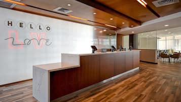 A reception desk with a 'HELLO LOVE' sign, wooden flooring, and a modern interior design.