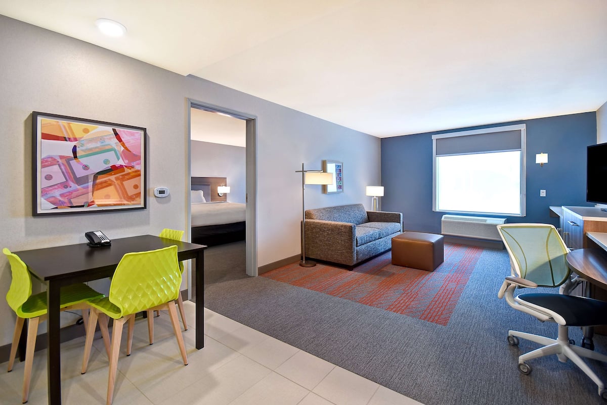 Een hotelkamer met een zithoek, een bank, een bureau en een groot raam.