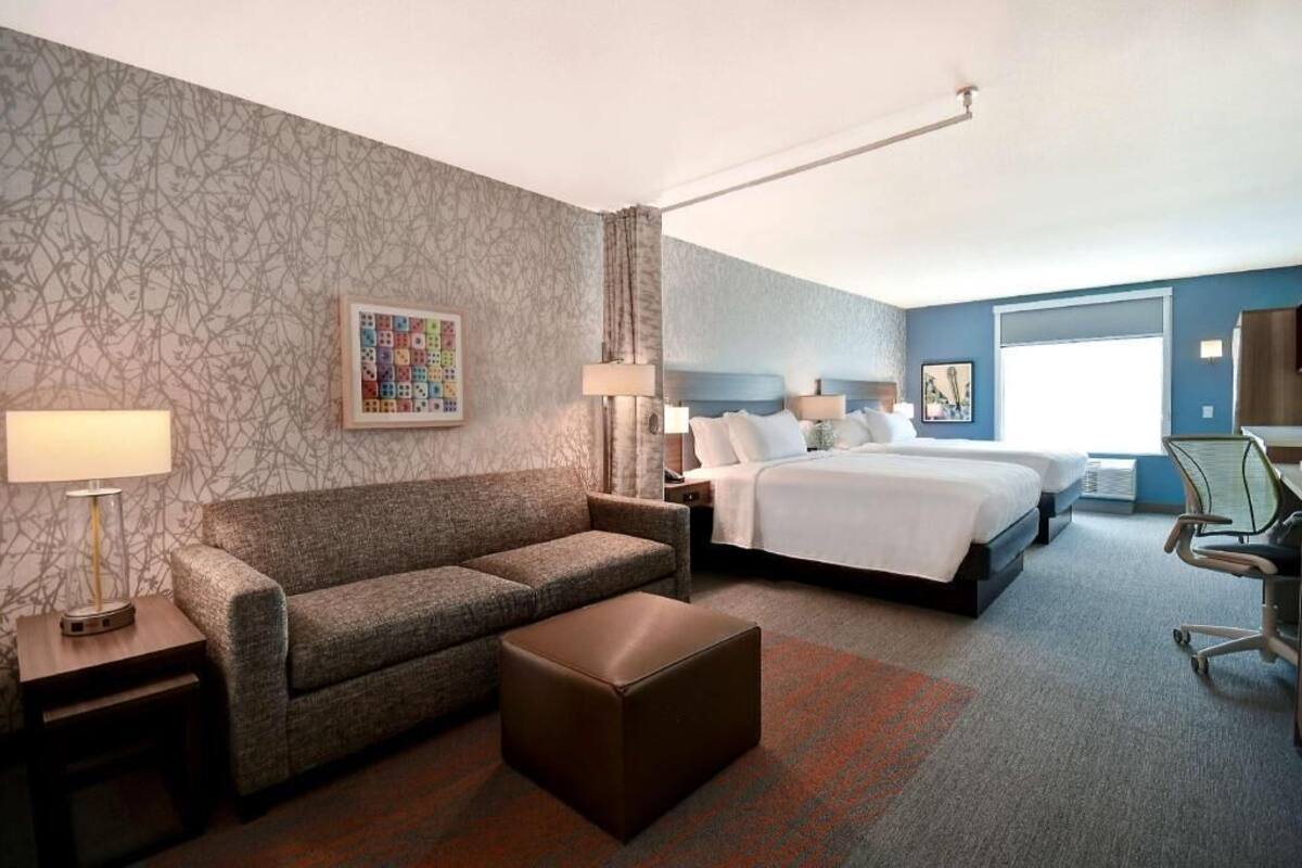 Een hotelkamer met een bed, een slaapbank, een bureau en een stoel.