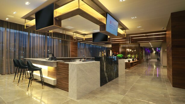 A modern hotel lobby with a reception desk, bar area, and seating. - Hilton Garden Inn Monterrey Obispado (Monterrey)