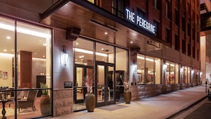 A hotel entrance with glass doors, a sign reading "THE PEREGRINE," and large potted plants on the sidewalk.