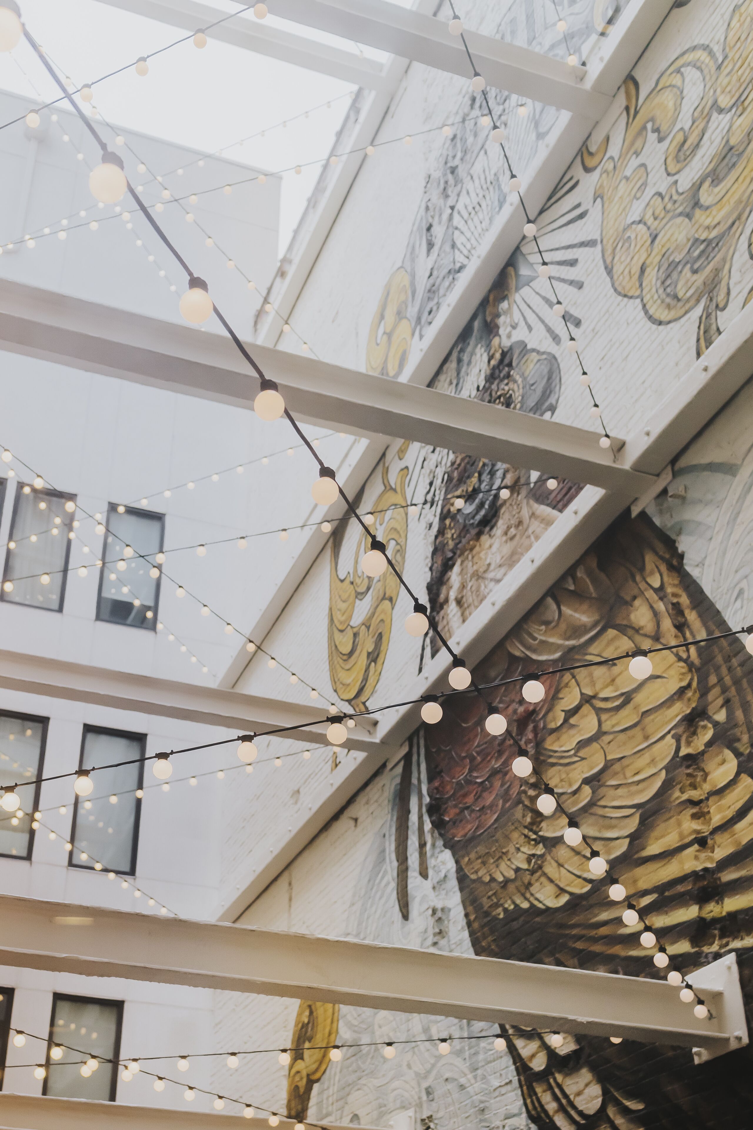 A building with a mural of a bird and string lights.