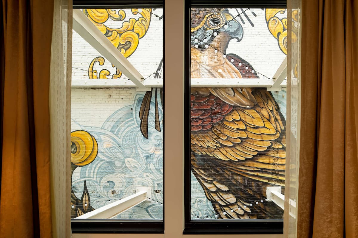 A window with a mural of a bird and abstract patterns.