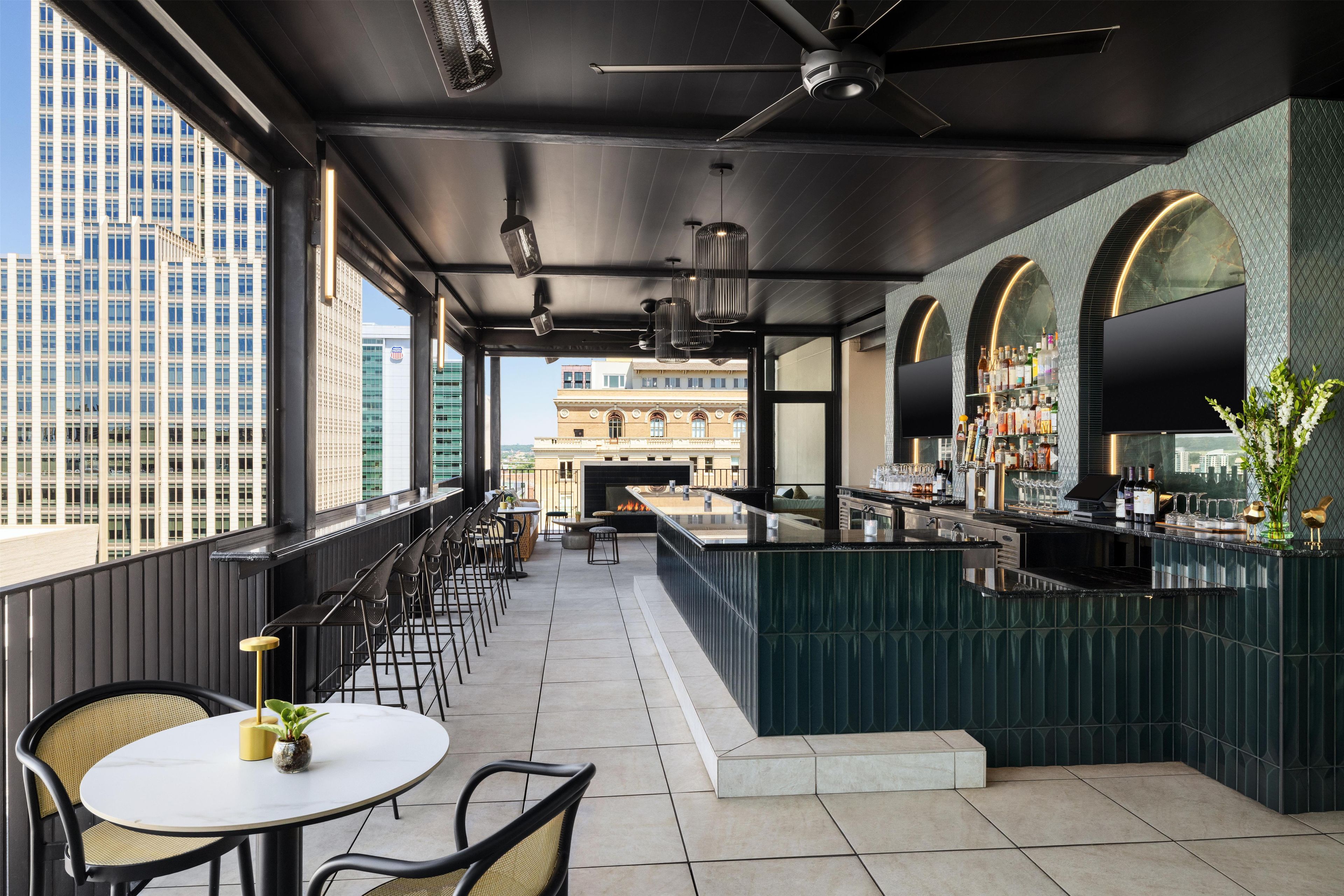 Un bar en la azotea con barra, zona de estar y vistas de la ciudad.