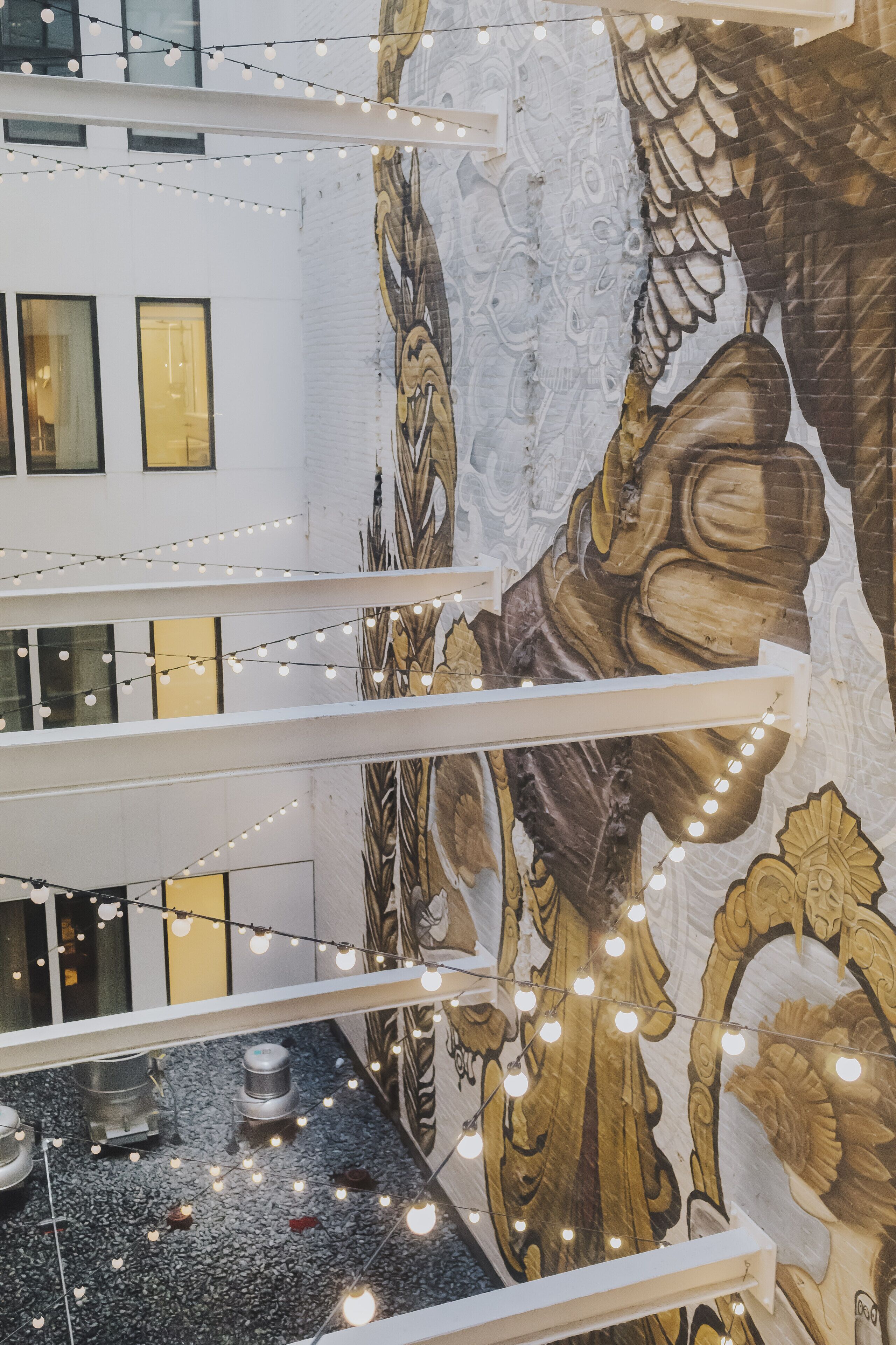 A multi-level interior with a decorative mural, string lights, and a water feature.