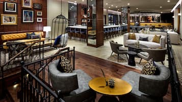A spacious lobby with a bar area, seating arrangements, and a staircase.