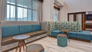 A modern interior with a sofa, ottoman, and round table. - Hampton Inn & Suites Tampa Riverview Brandon (Tampa)