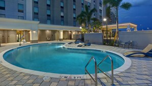 A hotel pool area with a clear pool, lounge chairs, and a building with a 'Marriott' sign. - Hampton Inn & Suites Tampa Riverview Brandon (Tampa)
